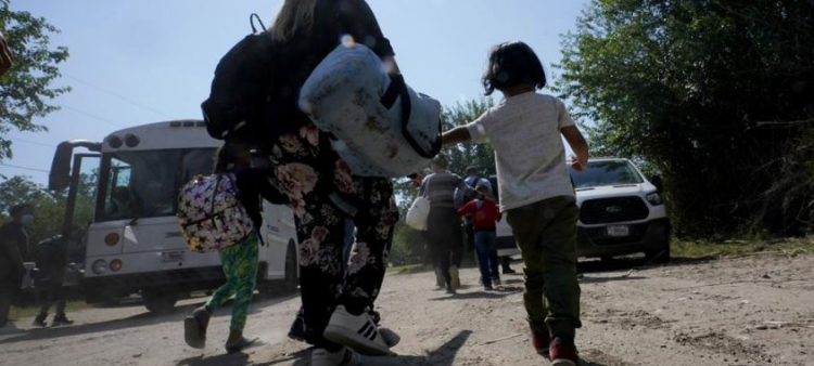 Una familia de migrantes venezolanos se dirige hacia un autobús de la Patrulla Fronteriza después de que cruzaran con otras personas de México hacia Estados Unidos