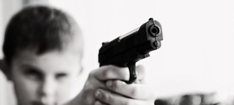 Menor de edad sosteniendo un arma de fuego. Imagen ilustrativa.