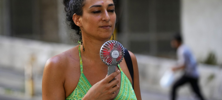 Una mujer se refresca con un ventilador eléctrico durante un día de calor sofocante en Beirut