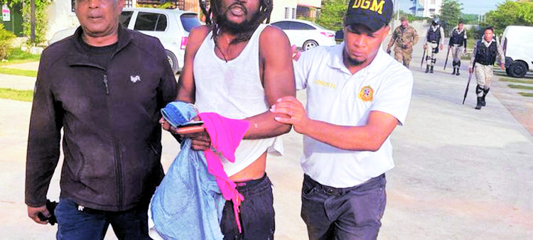 Oficiales de Migración conducen a un hombre que fue detenido durante una redada y que presumen es haitiano, para ser repatriado.