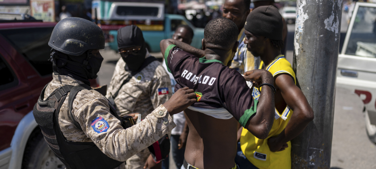 policía inspecciona a un hombre en busca de armas, en Puerto Príncipe