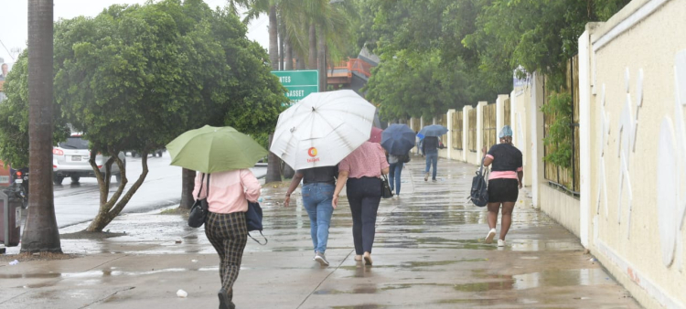 Personas caminando bajo la lluvia en el Distrito Nacional