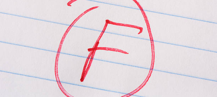 Grado "F" escrito con bolígrafo rojo sobre papel de cuaderno.