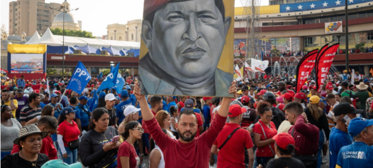 Un simpatizante de Nicolas Maduro sostiene un cuadro con la imagen de Hugo Chavez delante del Consejo Nacional Electoral (CNE) el 25 de marzo de 2024.