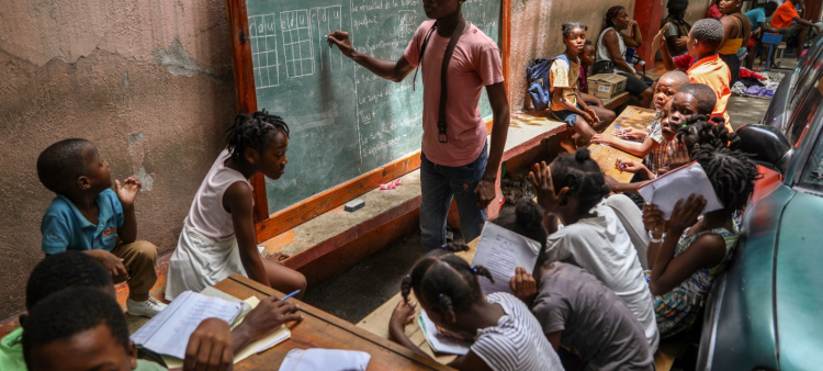 Un maestro enseña matemáticas a niños que viven en un refugio para familias que huyeron de sus hogares debido a la violencia de las pandillas, en Puerto Príncipe.