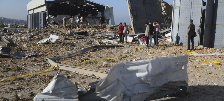 Un grupo de personas se congregan junto a un hangar alcanzado por un ataque aéreo israelí, en Jiyeh, Líbano, ayer.