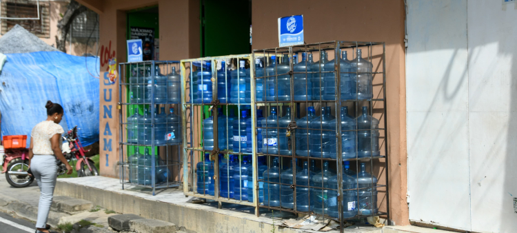 Botellones de agua para consumo humano expuesta a la venta al descubierto en un anaquel de colmado en Santo Domingo Este.