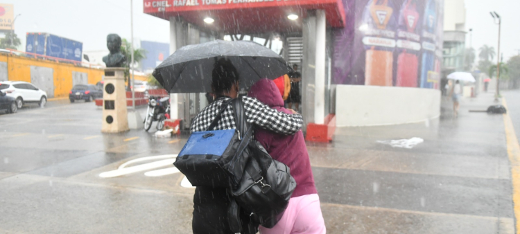 Dos mujeres se cubren de la lluvia mientras caminan a una estación del Metro de Santo Domingo.