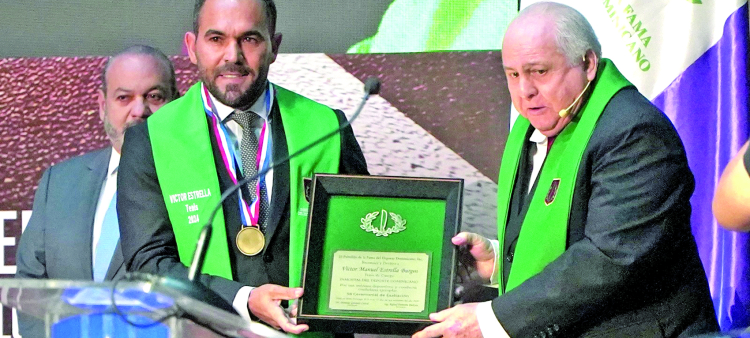 Víctor Estrella muestra placa de reconocimiento de manos del presidente de honor Luis Esmurdoc.