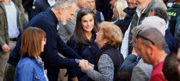 El rey Felipe VI de España habla con una mujer junto a la reina Letizia, ayer en Chiva.