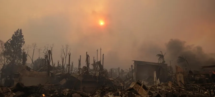 El sol brilla a través del humo sobre las ruinas de las casas del incendio forestal.