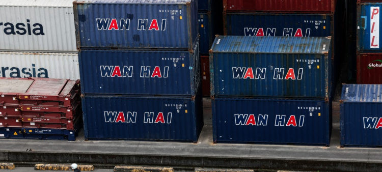 Un hombre conduce un scooter junto a contenedores de envío en el puerto de Keelung el 16 de enero de 2026.