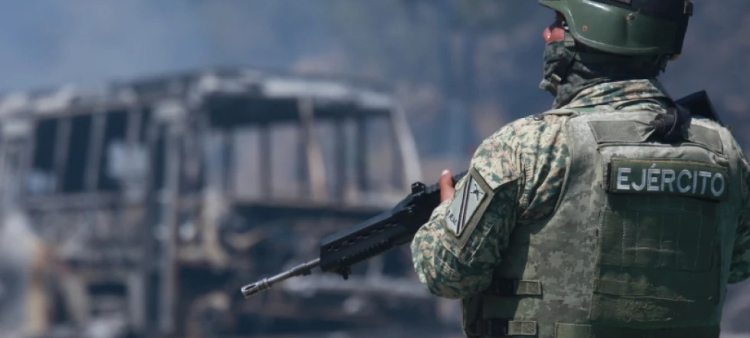 Un soldado vigila un vehículo calcinado tras ser incendiado en Cointzio, Michoacán, México, el domingo 22 de febrero de 2026, tras la muerte del líder del Cártel Jalisco Nueva Generación, Nemesio Oseguera, conocido como "El Mencho".