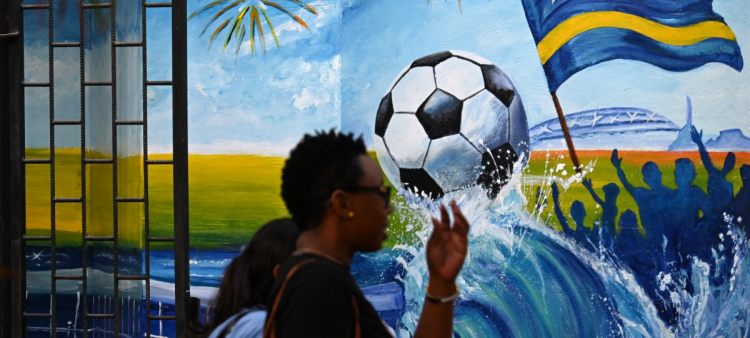 Mujeres caminan junto a un mural que representa un balón de fútbol y la bandera de Curazao en Willemstad, en el Caribe neerlandés, el 10 de abril de 2026.