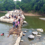 Cruzan río Camú usando un puente de tablitas