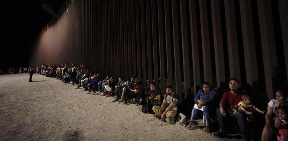 ARCHIVO - Migrantes esperan junto a un muro fronterizo el 23 de agosto del 2022, tras cruzar desde México cerca de Yuma, Arizona. Un aumento en la migración de Venezuela, Cuba y Nicaragua en septiembre elevó el número de cruces ilegales de la frontera al nivel más alto que se haya registrado en un año fiscal, de acuerdo con el Servicio de Aduanas y Protección Fronteriza de Estados Unidos. (AP Foto/Gregory Bull)
ARCHIVO - Migrantes esperan junto a un muro fronterizo el 23 de agosto del 2022, tras cruzar desde México cerca de Yuma, Arizona. Un aumento en la migración de Venezuela, Cuba y Nicaragua en septiembre elevó el número de cruces ilegales de la frontera al nivel más alto que se haya registrado en un año fiscal, de acuerdo con el Servicio de Aduanas y Protección Fronteriza de Estados Unidos. (AP Foto/Gregory Bull)