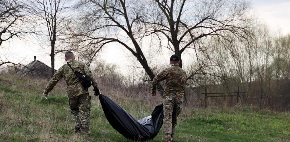 EDITORS NOTE: Graphic content / Members of Civil-Military Cooperation team carry remains of a Russian soldier in the village of Synykha, Kharkiv region, on April 8, 2023, amid the Russian invasion of Ukraine. (Photo by Sergiy KOZLOV / AFP)