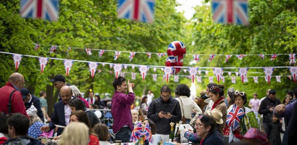 Varias personas platican y comparten comida durante las celebraciones por la coronación del rey Carlos III el domingo 7 de mayo de 2023, en Londres