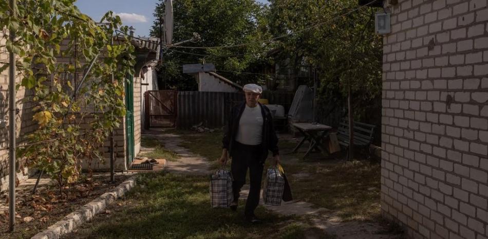 Sergiy lleva bolsas mientras es evacuado de su casa por miembros de la Cruz Roja ucraniana, en el pueblo de Bohuslavka, al sur de Kupiansk, en la región de Kharkiv, el 28 de septiembre de 2023