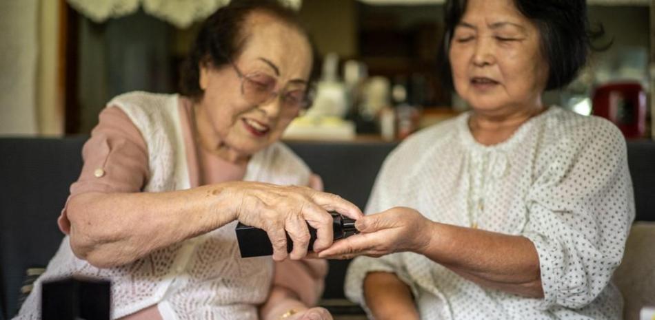 Esta foto muestra a la asesora de belleza Tomoko Horino (izquierda), de 100 años, presentando productos a su clienta, en la ciudad de Fukushima