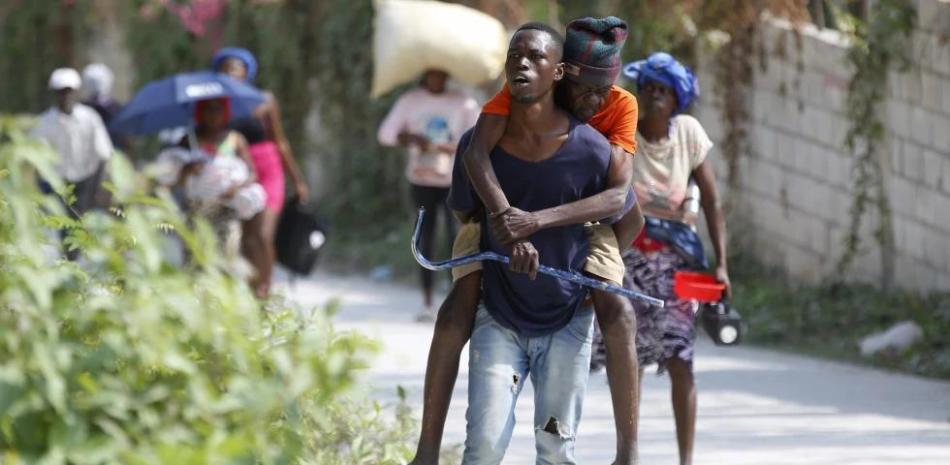 Un residente carga en su espalda a un anciano mientras huyen de su vivienda para evitar los enfrentamientos entre grupos armados, el miércoles 31 de enero de 2024, en el distrito de Petion-Ville, Haití.