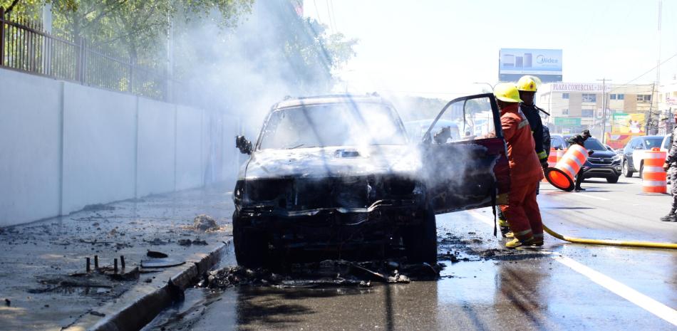 El Cuerpo de Bomberos del Distrito Nacional controlan las llamas de un vehículo incendiado en la avenida 27 de Febrero, próximo a avenida Leopoldo Navarro.