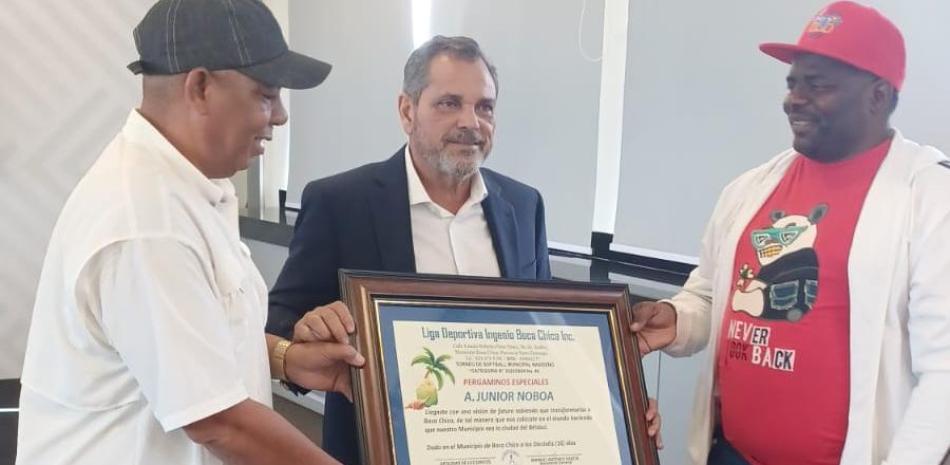 El Comisionado Nacional de Béisbol, Junior Noboa al momento de ser homenajeado por Félix Amancio y Manuel García, ejecutivos de la Liga Deportiva Ingenio Boca Chica.