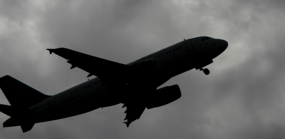 Imagen ilustra un avión en medio del cielo nublado.