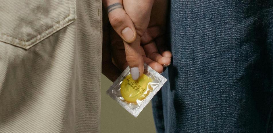 Dos personas con un preservativo en la mano