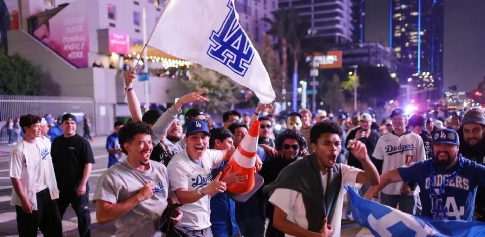 Un grupo de fanáticos con banderas y celulares celebran la conquista del campeonato por parte de los Dodgers.