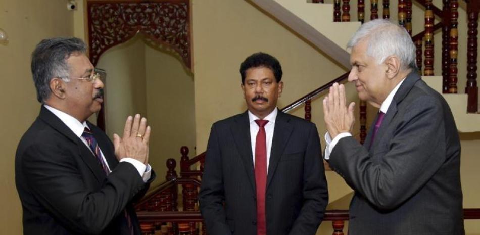 En esta foto distribuida por la presidencia de Sri Lanka, el presidente interino Ranil Wickremesinghe, derecha, saluda al presidente de la Corte Suprema, Jayantha Jayasuriya durante la ceremonia de juramentación en Colombo, Sri Lanka, viernes 15 de julio de 2022. (Presidencia de Sri Lanka via AP)