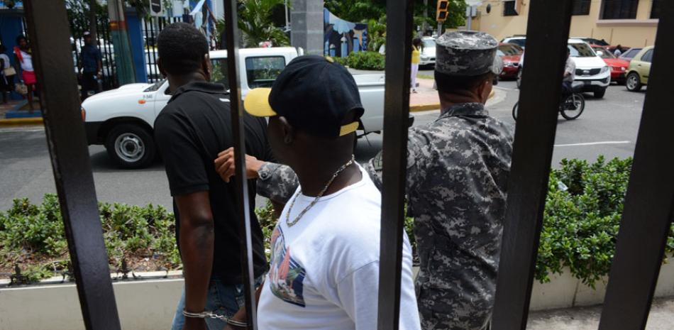 Arrestados. Dos haitianos son conducidos presos, en la capital, por violar el orden en las filas para aplicar a estatus legal aquí.
