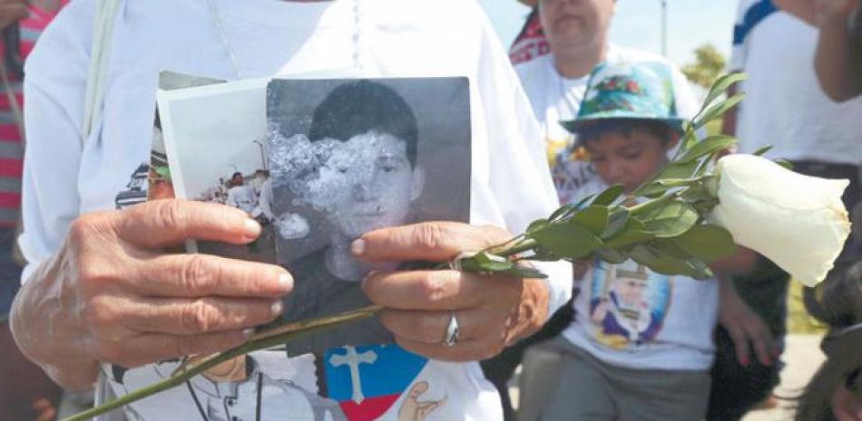 Bendición. Una mujer sostiene una rosa blanca y fotografías de su hijo en espera de que el papa Francisco las bendiga en el parque Samanes, de Guayaquil, donde el pontífice ofició una misa, ayer.