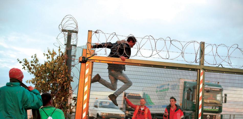 Vallas. Un migrante salta una verja mientras intenta llegar al Eurotúnel en Calais, al norte de Francia, ayer. El Gobierno británico invertirá unos 10 millones de euros en proteger a camiones y levantar una
valla de seguridad.