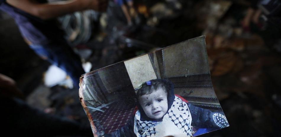 Un familiar muestra una fotografía del bebé palestino de 18 meses Ali Dawabsha, que murió en su casa en un incendio provocado por colonos extremistas israelíes, en la población palestina de Douma, junto a Nablus, hoy, 31 de julio de 2015. EFE