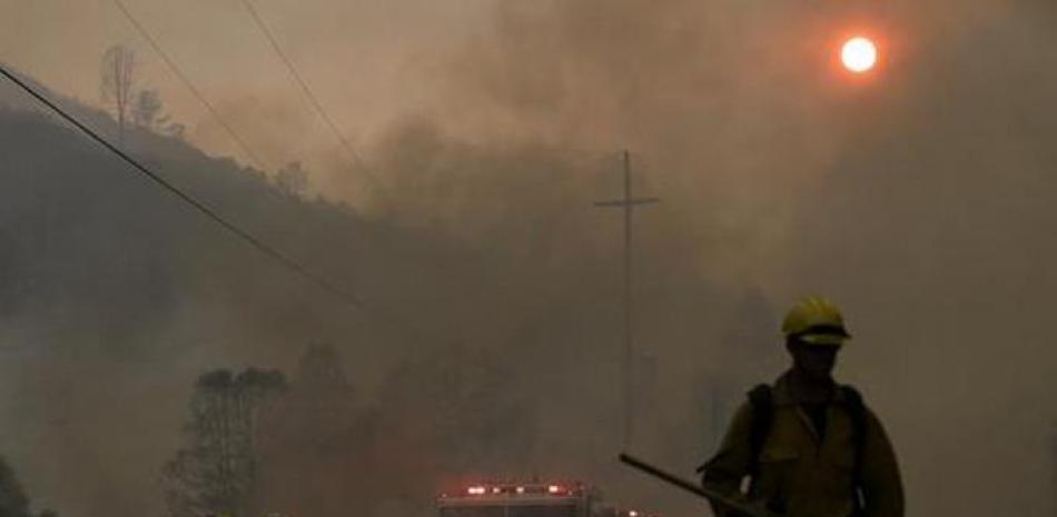 Bomberos caminan bajo el humo causado por incendios en la calle Morgan Valley cerca de Lower Lake, California. Una serie de incendios se intensificaron por la vegetación seca, temperaturas elevadas y vientos erráticos. (Foto AP/Jeff Chiu).