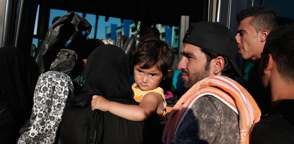 Refugiados intentan entrar en un autocar tras su llegada en transbordador al puerto de Pireo, cerca de Atenas, el 29 de agosto de 2015. AP