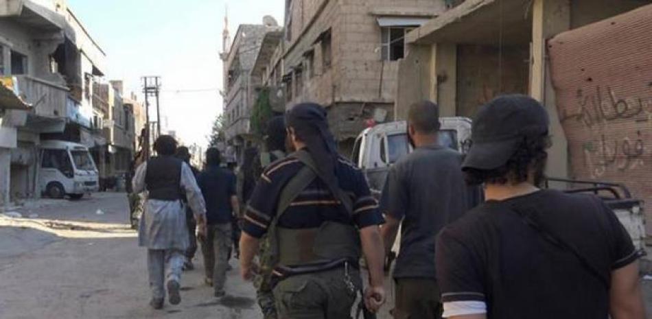 Combatientes del grupo Estado Islámico avanzan por una calle en el vecindario de Qadam, en Damasco, Siria, según esta imagen que difundió el domingo 30 de agosto de 2015 la agencia noticiosa Rased News Network en una página de Facebook afiliada a esa organización armada. (Vía AP Foto/Rased News Network).
