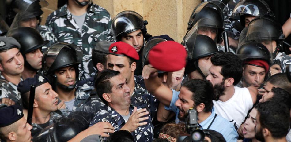Basura. Manifestantes antigubernamentales enfrentan a la policía antimotines frente al Ministerio de Ambiente, ayer en Beirut.