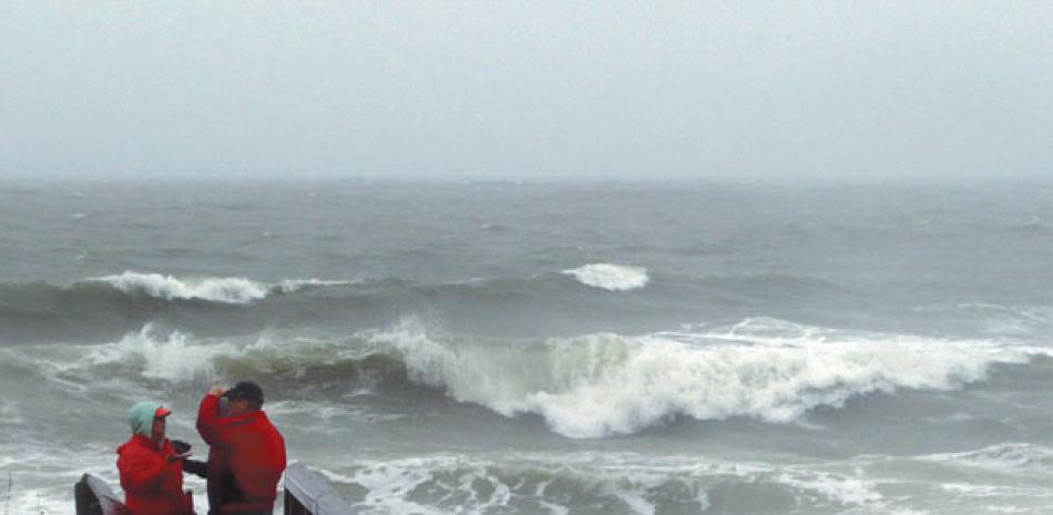 Personas observan las olas causadas por el mal tiempo en Carolina Beach, ayer.