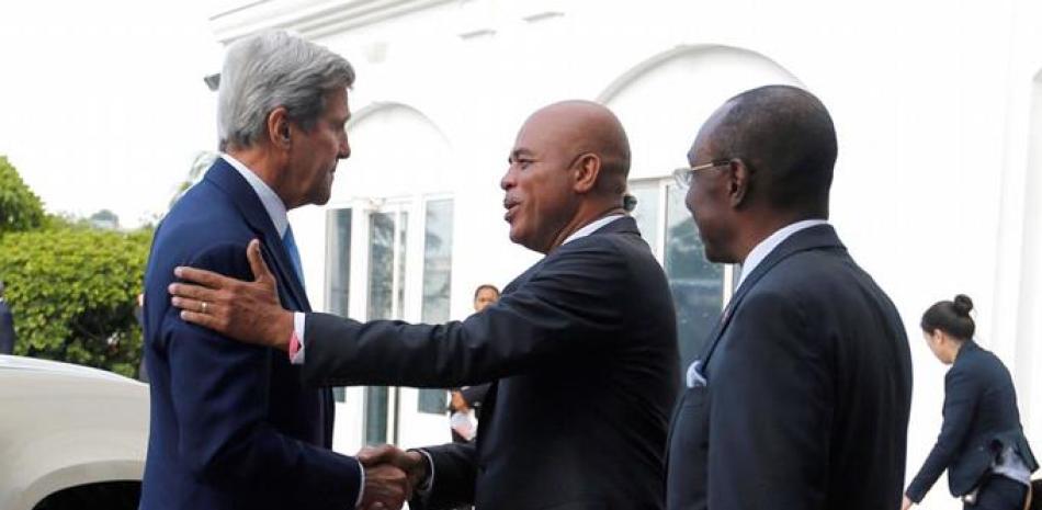 Visita. El secretario de Estado de Estados Unidos, John Kerry, al centro, saluda al presidente de Haití, Michel Martelly, luego de llegar a los terrenos del Palacio Nacional en Puerto Príncipe, ayer. Observa el primer ministro Evans Paul.