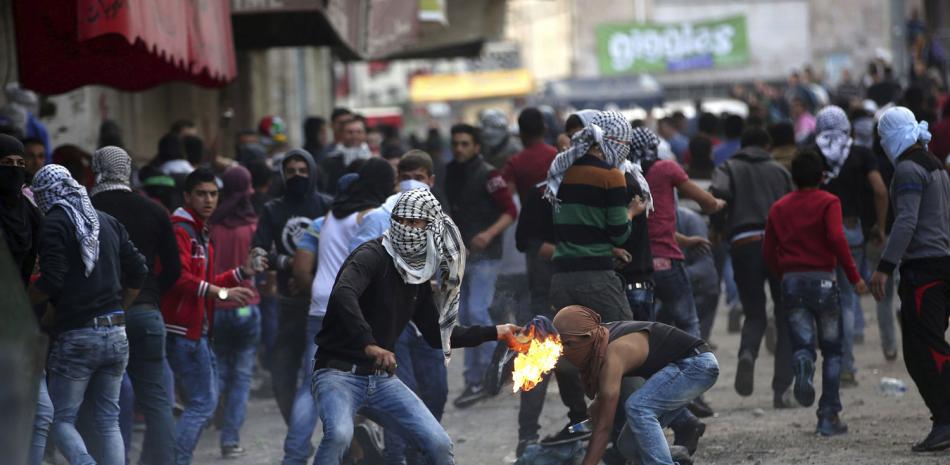 Un manifestante palestino lanza un cóctel molotov contra miembros del Ejército israelí durante un enfrentamiento en Hebrón, Palestina, hoy 9 de octubre de 2015.