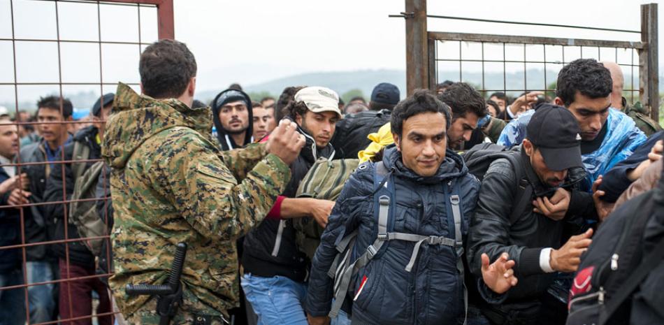 Control. Policías de Macedonia controlan a una multitud de migrantes y refugiados, luego de que éstos cruzaran la frontera griega hacia Gevgelija, ayer.