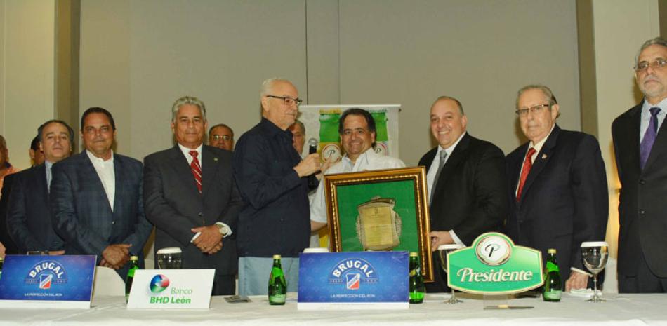 El doctor Leonardo Matos Berrido entrega una placa de reconocimiento a Miguel Feris Chalas, hijo del extinto empresario Miguel Feris Iglesias a quien está dedicado el venidero torneo de béisbol invernal.