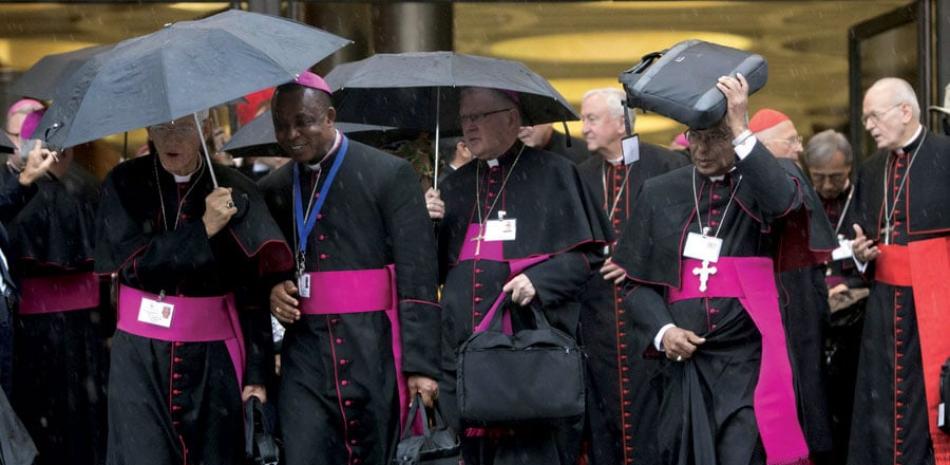 Lluvia. Cardenales y obispos se protegen de la lluvia al térimino de la sesión matutina del sínodo de obispos en el Vaticano, antier.