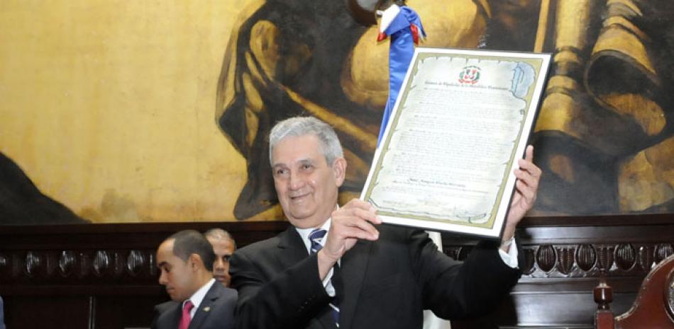 El doctor José Joaquín Puello levanta el pergamino de reconocimiento que le otorgara la Cámara de Diputado durante un multitudinario acto celebrado ayer en el Salón de Asamblea Nacional.