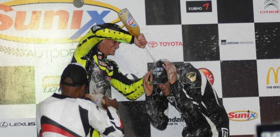 Los ganadores de la carrera de motos celebran en el podium luego de su triunfo.