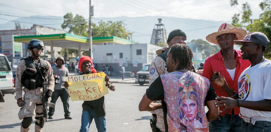 Violencia. Policías tratan de controlar a manifestantes durante una protesta ayer, en Puerto Príncipe, donde se desataron graves incidentes como lanzamiento de piedras y quema de neumáticos.