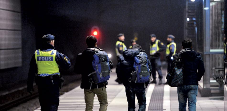 Migrantes. La policía escolta a tres hombres en la estación de trenes en Hullie, en Malmo, Suecia, el 17 de diciembre pasado.