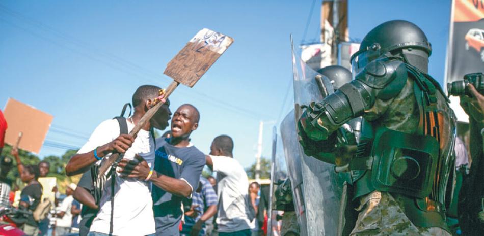 Marcha. Policías bloquean el paso a manifestantes que protestan en Puerto Príncipe, para pedir la renuncia del presidente Michel Martelly.